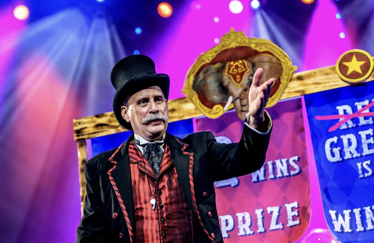 David Williamson welcomes the audience as Circus 1903’s ringmaster beneath colorful stage lights